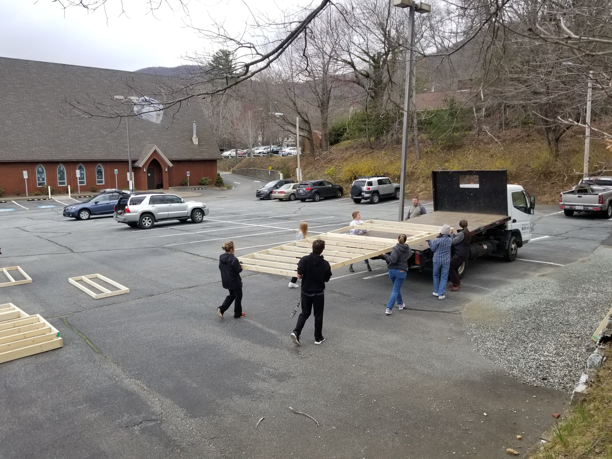Students carrying a completed wall to a flatbed truck.