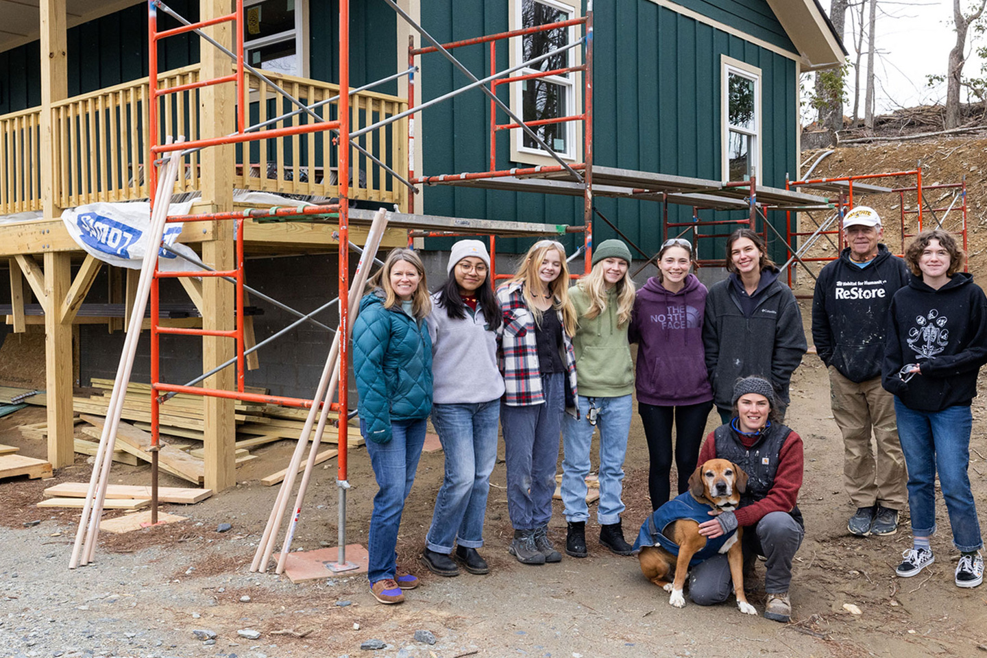 A group of workers stand in front of a home under construction 